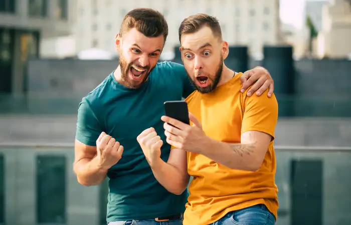 to mænd kigger på deres telefon glade for at have vundet i bingo